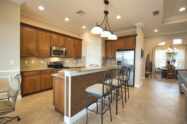 kitchen with hanging light fixtures, stainless steel appliances, light stone countertops, and a kitchen island