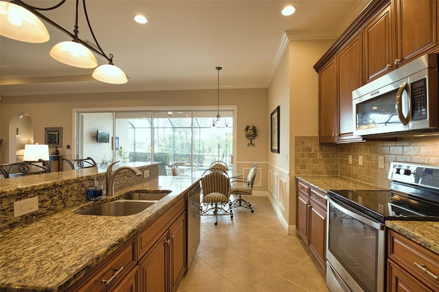 kitchen with pendant lighting, appliances with stainless steel finishes, sink, and light stone counters