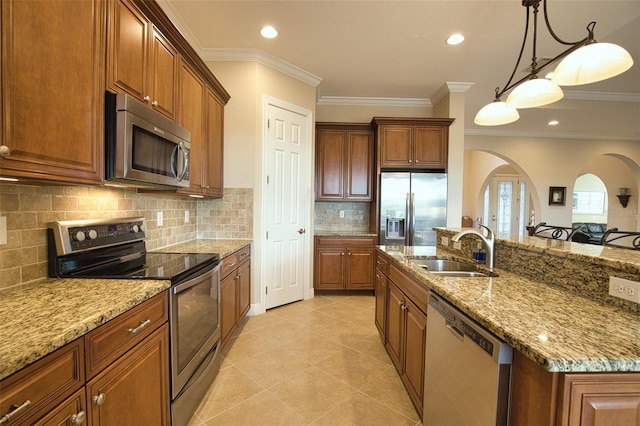 kitchen featuring sink, pendant lighting, stainless steel appliances, light stone countertops, and backsplash