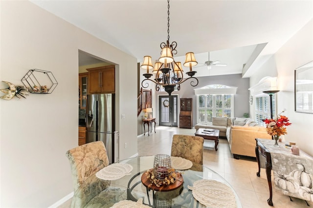 tiled dining area with ceiling fan with notable chandelier and lofted ceiling