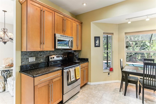 kitchen featuring decorative light fixtures, a healthy amount of sunlight, track lighting, and appliances with stainless steel finishes