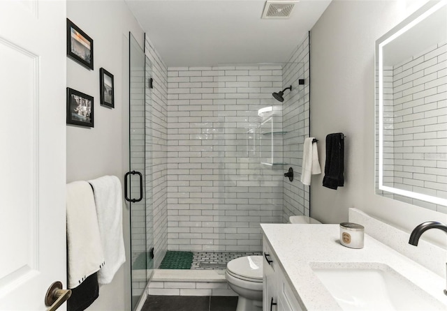 bathroom with tile patterned floors, vanity, toilet, and a shower with shower door