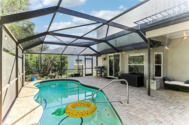 view of pool with glass enclosure and a patio