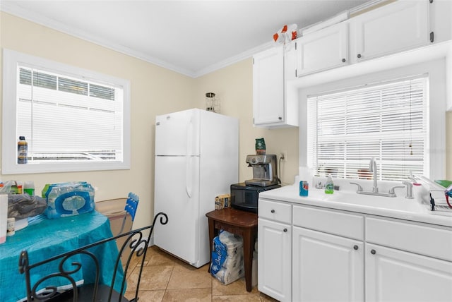 kitchen with white refrigerator, crown molding, sink, light tile patterned flooring, and white cabinetry