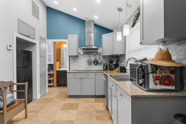 kitchen featuring black fridge, gray cabinetry, sink, wall chimney range hood, and pendant lighting