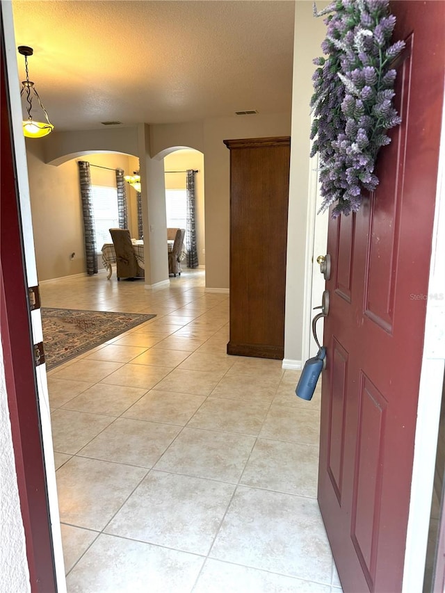 foyer featuring light tile patterned flooring and a textured ceiling