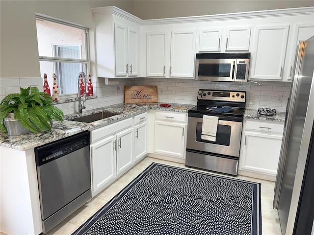 kitchen with white cabinetry, sink, stainless steel appliances, light stone counters, and decorative backsplash