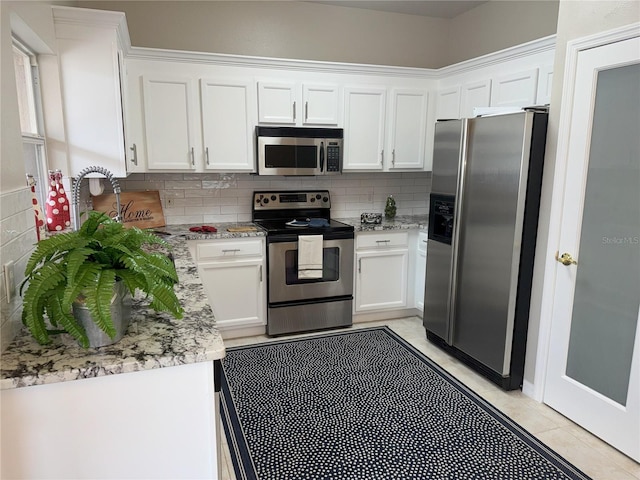 kitchen with decorative backsplash, stainless steel appliances, white cabinetry, and light stone counters