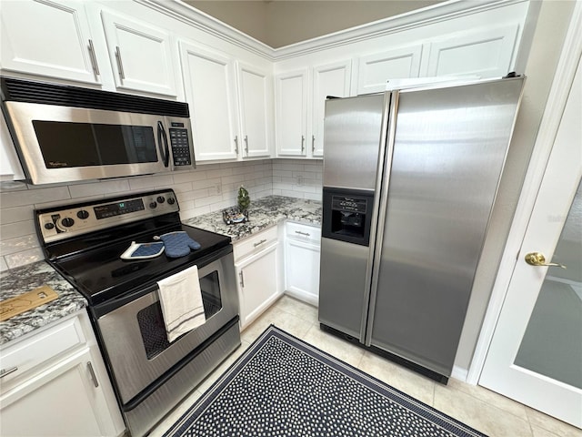 kitchen with light stone counters, white cabinetry, stainless steel appliances, and light tile patterned floors