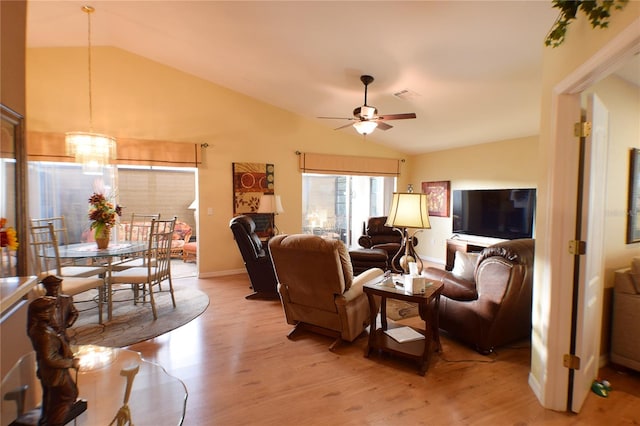 living room with light hardwood / wood-style flooring, ceiling fan with notable chandelier, and vaulted ceiling