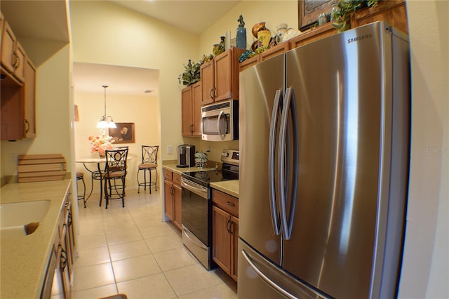 kitchen featuring stainless steel appliances, sink, pendant lighting, light tile patterned floors, and a chandelier