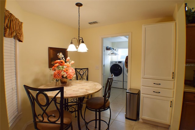 dining space with washer and dryer, an inviting chandelier, and light tile patterned flooring