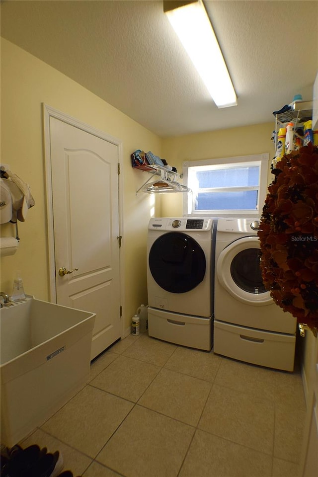 laundry area featuring sink, independent washer and dryer, a textured ceiling, and light tile patterned floors