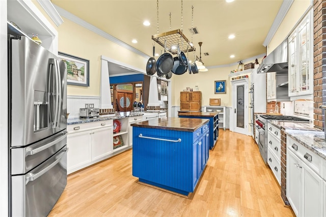 kitchen with a center island, wooden counters, stainless steel refrigerator with ice dispenser, blue cabinetry, and white cabinetry