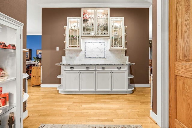 kitchen with white cabinets, crown molding, backsplash, and light hardwood / wood-style flooring