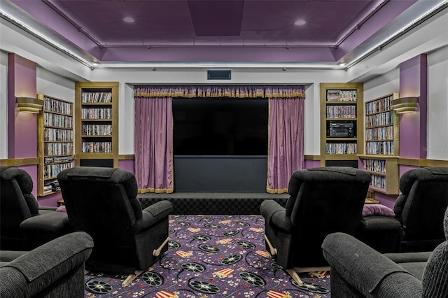 carpeted home theater room with built in features and a tray ceiling