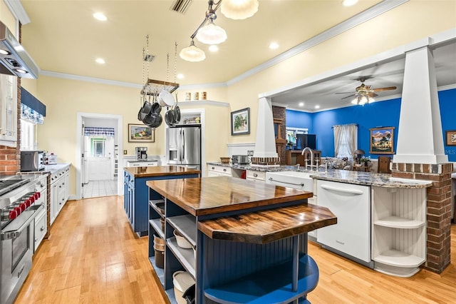 kitchen featuring butcher block countertops, white cabinetry, dishwasher, stainless steel fridge, and kitchen peninsula