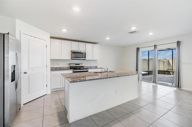 kitchen with white cabinetry, sink, dark stone countertops, a center island with sink, and appliances with stainless steel finishes