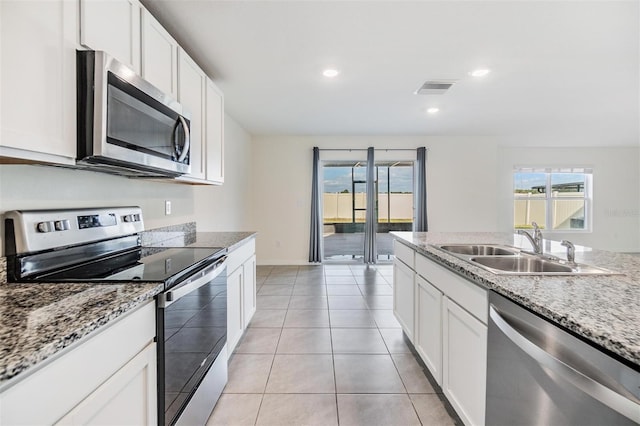 kitchen featuring light stone countertops, stainless steel appliances, sink, light tile patterned floors, and white cabinetry