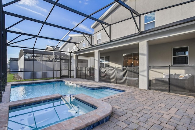 view of pool with glass enclosure, an in ground hot tub, and a patio