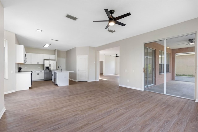 unfurnished living room with ceiling fan, sink, and light wood-type flooring