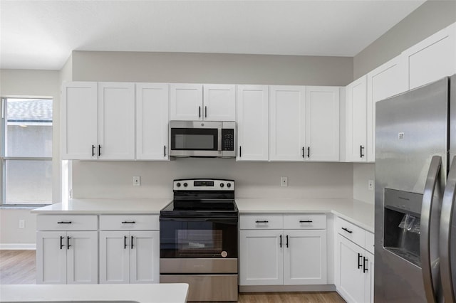 kitchen with white cabinetry, stainless steel appliances, and light hardwood / wood-style floors