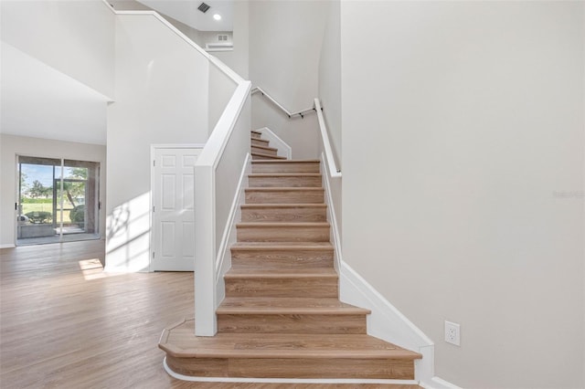 stairway featuring hardwood / wood-style floors and a towering ceiling