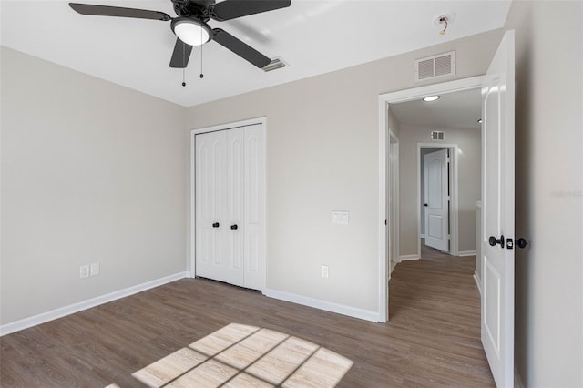 unfurnished bedroom featuring ceiling fan, dark hardwood / wood-style flooring, and a closet