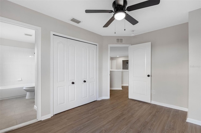 unfurnished bedroom with ceiling fan, dark hardwood / wood-style flooring, ensuite bathroom, and a closet