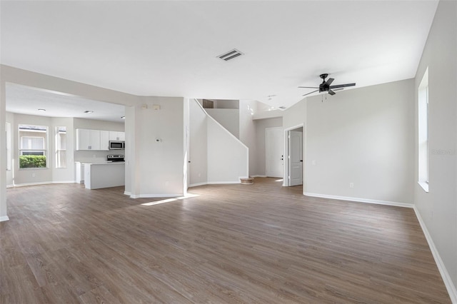 unfurnished living room with baseboards, visible vents, a ceiling fan, and wood finished floors