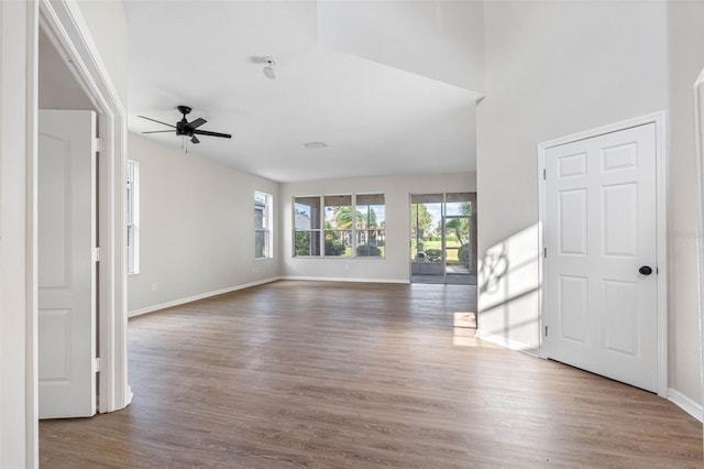 unfurnished living room with a ceiling fan, baseboards, and wood finished floors