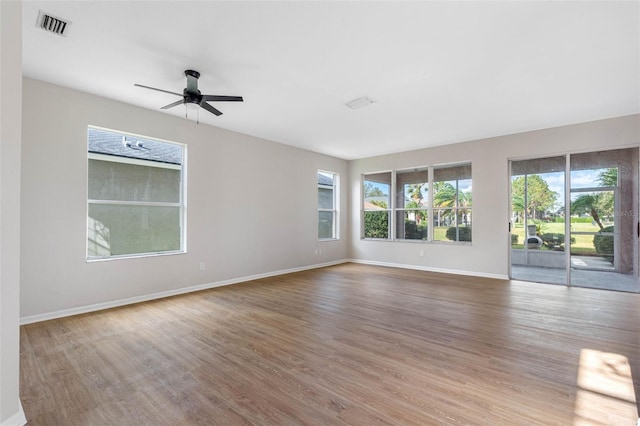 spare room with a ceiling fan, baseboards, visible vents, and wood finished floors