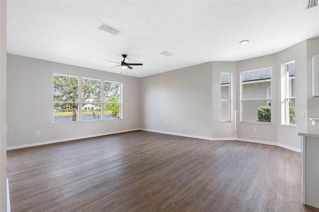 empty room featuring dark wood-type flooring, ceiling fan, and baseboards