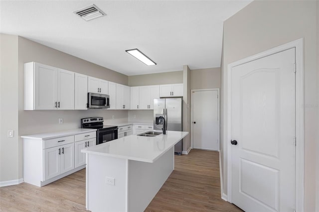 kitchen with stainless steel appliances, light countertops, a center island with sink, and visible vents