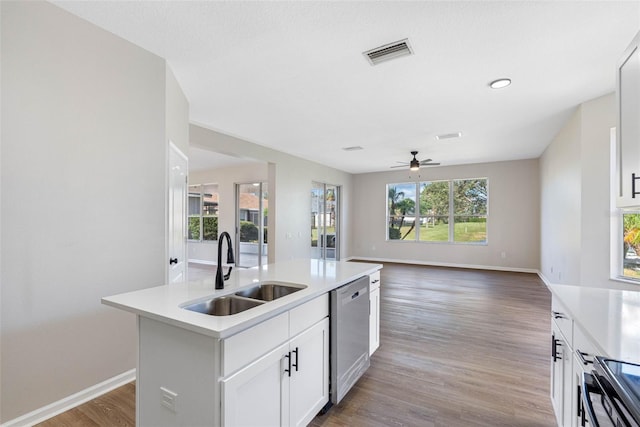 kitchen featuring an island with sink, a sink, light countertops, white cabinetry, and stainless steel dishwasher