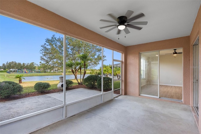 unfurnished sunroom featuring ceiling fan and a water view