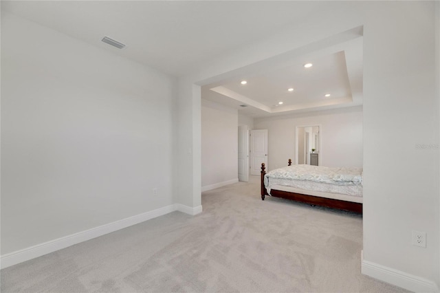 unfurnished bedroom with a tray ceiling and light colored carpet