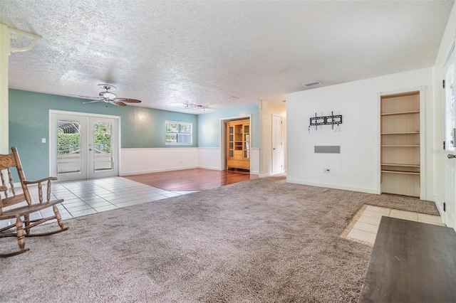 unfurnished living room featuring a textured ceiling, carpet floors, french doors, and ceiling fan