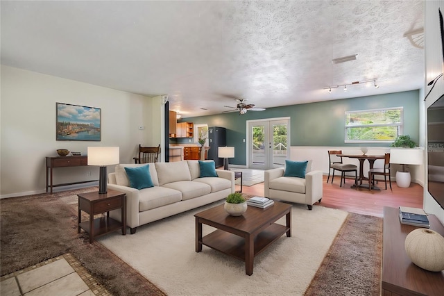 living room with a wealth of natural light, ceiling fan, light hardwood / wood-style floors, and a textured ceiling