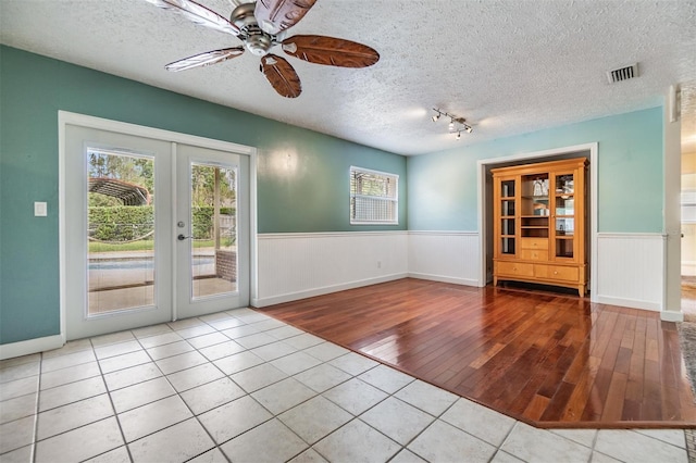 doorway featuring ceiling fan, light hardwood / wood-style floors, a textured ceiling, and french doors