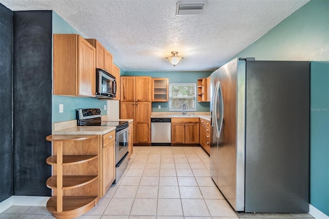 kitchen with sink, light tile patterned flooring, a textured ceiling, and appliances with stainless steel finishes