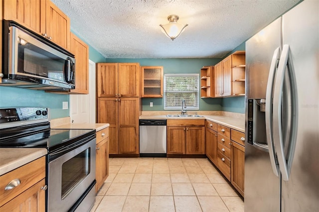 kitchen featuring a textured ceiling, light tile patterned floors, sink, and appliances with stainless steel finishes