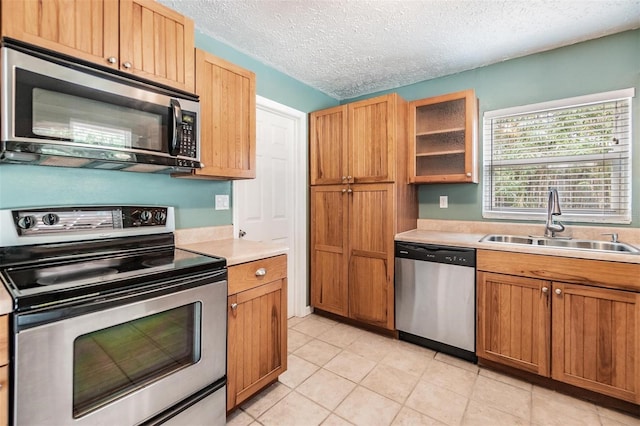 kitchen featuring a textured ceiling, light tile patterned floors, sink, and appliances with stainless steel finishes