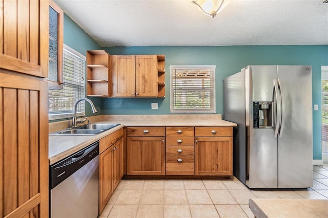 kitchen with a healthy amount of sunlight, sink, light tile patterned floors, and stainless steel appliances