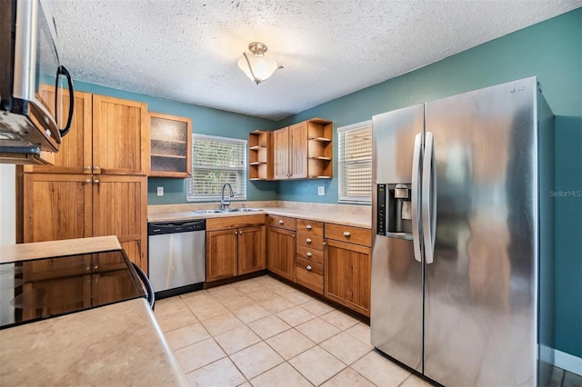 kitchen with appliances with stainless steel finishes, a textured ceiling, light tile patterned floors, and sink