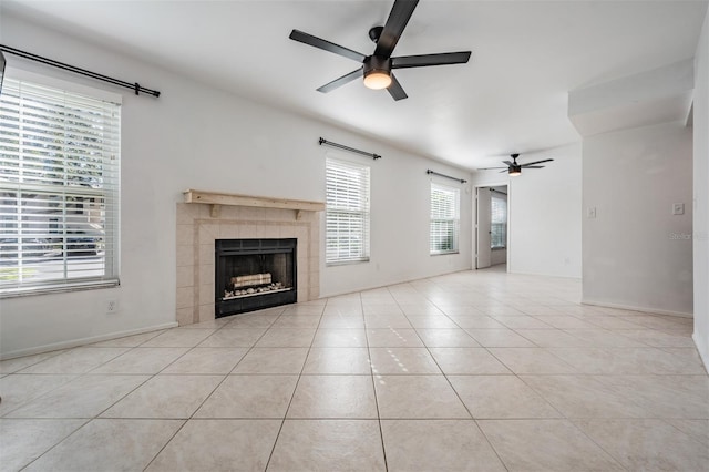 unfurnished living room with tile patterned floors, a tile fireplace, baseboards, and a ceiling fan