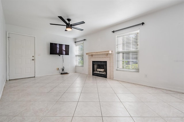 unfurnished living room with light tile patterned flooring, a healthy amount of sunlight, a tile fireplace, and a ceiling fan