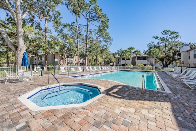 community pool with a patio area, a community hot tub, and fence