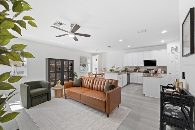 living room featuring ceiling fan, light hardwood / wood-style floors, and sink