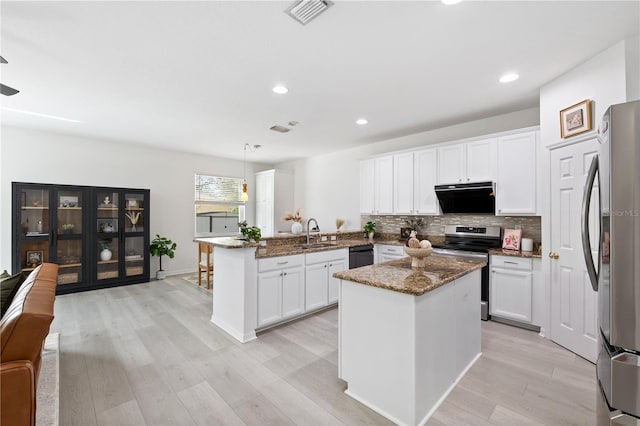 kitchen featuring kitchen peninsula, light wood-type flooring, black appliances, dark stone countertops, and a center island